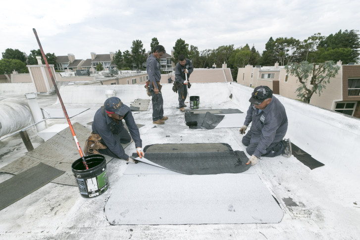 Roofers with Hull Brothers Roofing & Waterproofing resurface townhomes roofs at the Marina del Rey seaside community of Los Angeles on Tuesday, Aug. 25, 2015. While drought-plagued California is eager for rain, the forecast of a potentially Godzilla-like El Nino event has communities clearing out debris basins, urging residents to stock up on emergency supplies and even talking about how a deluge could affect the 50th Super Bowl. (AP Photo/Damian Dovarganes)